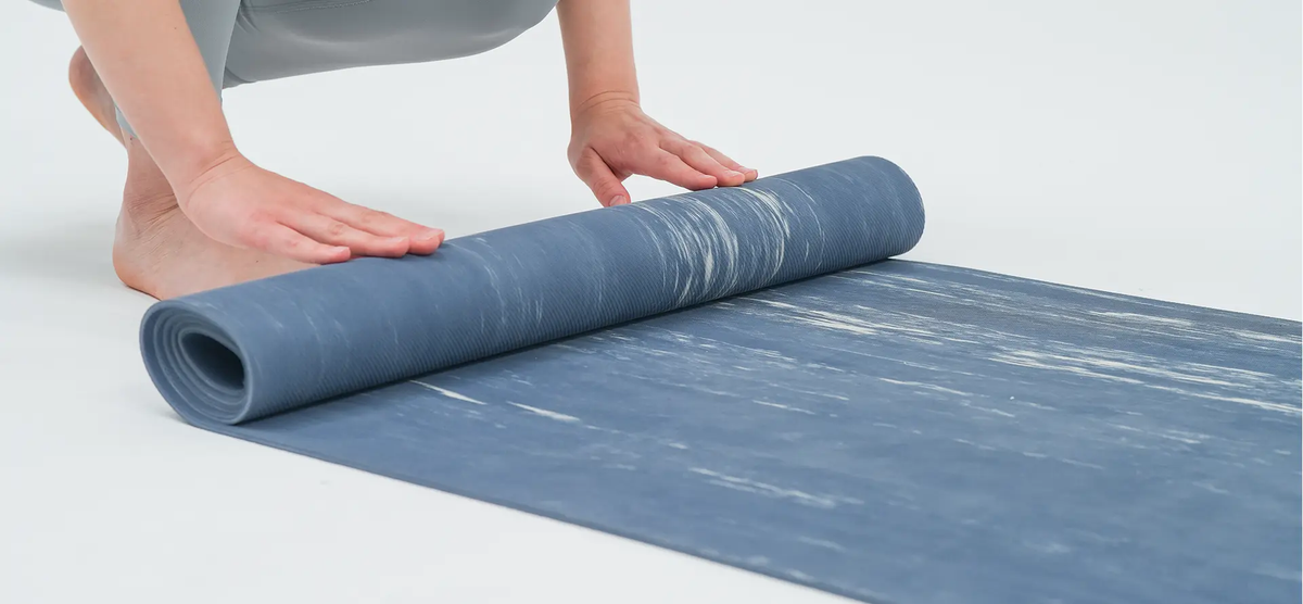 AEKE Ankle Yoga Mat in blue with a marbled white pattern being rolled up.